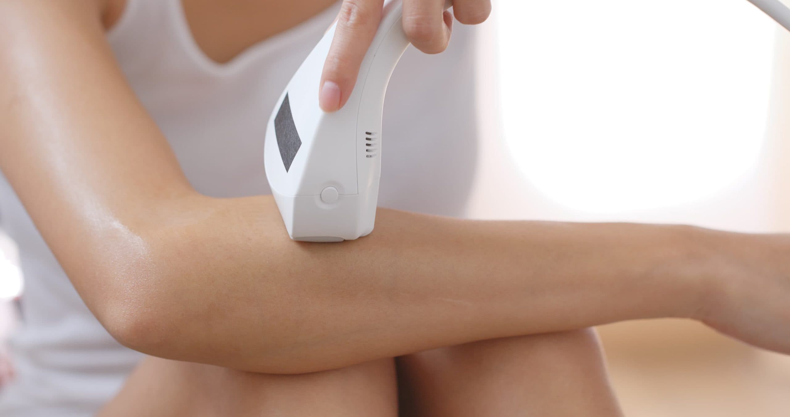 femme utilise épilateur lumière pulsée sur bras droit