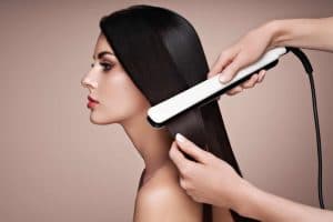 femme brune utilisant un lisseur vapeur professionnel